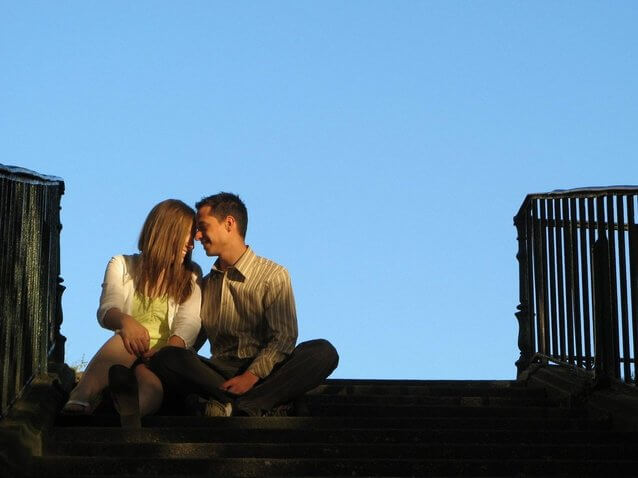 couple kissing while sitting at stairs.