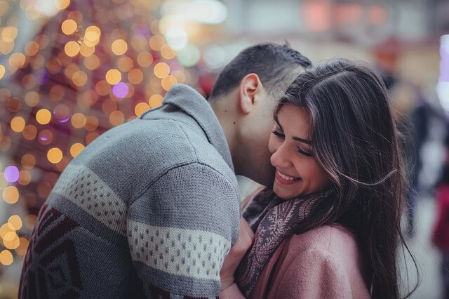 Boyfriend giving girlfriend a neck kiss.