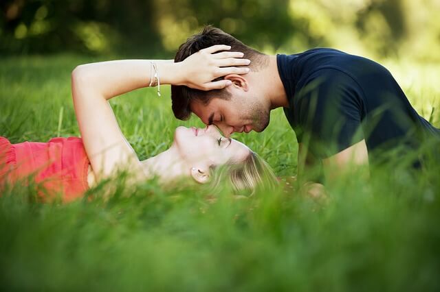 a couple laying in the grass kissing.