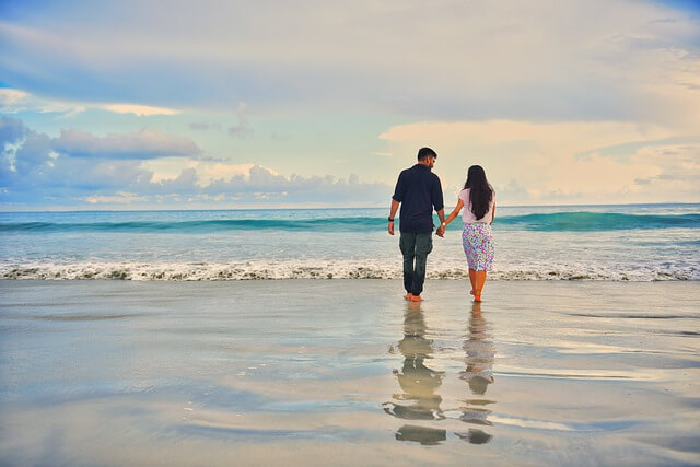 a couple holding hands at the beach.