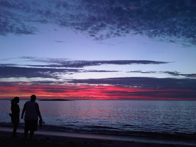 man and a woman staring down a sunset