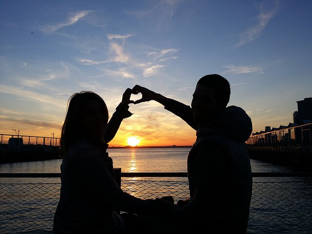 couple making a heart with their hands.