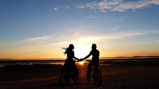 couple biking together and holding hands